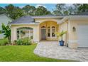 Well-kept home with manicured lawn, arched entrance, and a lovely paved driveway and walkway at 13038 Royal George Ave, Odessa, FL 33556