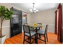 Dining room featuring wood floors, a modern chandelier, a table with four chairs, and black sliding door at 1308 Peachfield Dr, Valrico, FL 33596