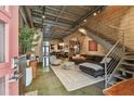Spacious living room featuring exposed brick walls, metal staircase, polished concrete floors, and modern furnishings at 2505 W Azeele St, Tampa, FL 33609