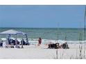 People relaxing on a sunny beach with umbrellas and chairs, enjoying the ocean view on a clear day at 504 67Th Ave # 4, St Pete Beach, FL 33706