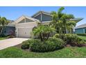 Inviting single-story home featuring a two-car garage and lush landscaping with palm trees at 5547 Silver Sun Dr, Apollo Beach, FL 33572