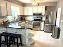 Modern kitchen featuring stainless steel appliances, granite countertops, an island, and white cabinets at 6880 Versailles N, Pinellas Park, FL 33781