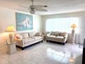Bright living room with tile floors, neutral-toned sofas, coastal decor, and lots of natural light at 6880 Versailles N, Pinellas Park, FL 33781