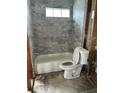 Bathroom tub/shower combo featuring updated gray marble-patterned tiling, along with glass shelves at 844 Bruce Ave, Clearwater Beach, FL 33767