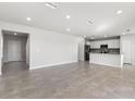 Bright open-concept living room with tiled floors and access to a modern kitchen at 9066 Rally Spring Loop, Wesley Chapel, FL 33545