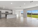 Bright open-concept living room with a modern kitchen, granite countertops, and stainless steel appliances at 9066 Rally Spring Loop, Wesley Chapel, FL 33545