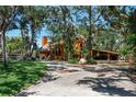 Two story home with a beautiful front yard, mature trees, and a covered carport at 11209 Spring St, Largo, FL 33774