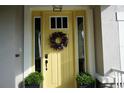 Bright yellow front door features decorative wreath, black hardware, and sidelight windows at 12327 Eagle Swoop Pl, Riverview, FL 33579