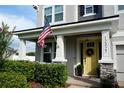 Inviting home exterior with a yellow front door, manicured landscaping and an American flag at 12327 Eagle Swoop Pl, Riverview, FL 33579