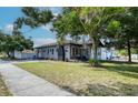 Exterior side view of a gray home with a well-maintained lawn, accented by a mature tree providing ample shade at 12595 95Th N St, Largo, FL 33773