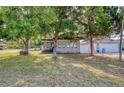 Landscaped front yard with mature trees framing a charming home exterior with a quaint front porch at 12595 95Th N St, Largo, FL 33773