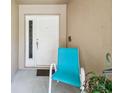 Inviting entryway with a white front door and a comfortable outdoor chair at 13003 Titleist Dr, Hudson, FL 34669