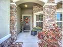 Close-up of the front door with stone detailing, a wreath, and planters at 13608 Artesa Bell Dr, Riverview, FL 33579