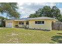 Charming one-story yellow home featuring a well-maintained lawn and a wooden fence at 1450 Seabreeze St, Clearwater, FL 33756