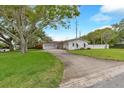 Single-story home featuring an attached garage, a well-maintained lawn, and a long, inviting driveway at 1666 Souvenir Dr, Clearwater, FL 33755