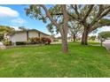 Well-manicured front lawn with mature trees and colorful landscaping leading to a charming single-story home at 1666 Souvenir Dr, Clearwater, FL 33755