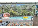 Relaxing screened-in pool area with comfortable seating, colorful decor, and lush backyard views at 1696 Hidden Springs Dr, Trinity, FL 34655