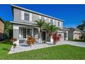 Two-story home boasting a grey exterior, complemented by tropical plants, white rock and a manicured lawn at 1712 Crossvine Ct, Trinity, FL 34655