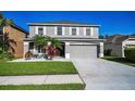 Two-story home featuring a grey color, manicured lawn, complemented by white rock and elegant tropical plants at 1712 Crossvine Ct, Trinity, FL 34655