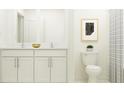 Bright bathroom featuring a toilet, double vanity, and modern art at 17573 Happytrails St, Land O Lakes, FL 34638