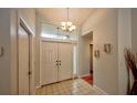 Bright foyer with tile flooring, double doors, and an elegant chandelier at 1955 Cobblestone Way, Clearwater, FL 33760