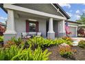 Inviting front porch with charming seating area surrounded by beautiful landscaping, creating a relaxing ambiance at 19836 Hidden Glen Dr, Land O Lakes, FL 34638