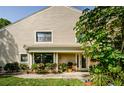 Inviting home exterior with a covered porch, lush landscaping, and large windows at 3174 Eagles Landing W Cir # 58, Clearwater, FL 33761