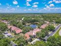 A beautiful aerial view showcasing the community pool, clubhouse, and a serene lake at 3505 Tarpon Woods Blvd # N405, Palm Harbor, FL 34685