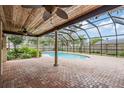 Covered, screened-in pool area with brick patio, ceiling fans, and lush landscaping at 3604 Arlington Oaks Ct, Tampa, FL 33618
