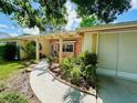 Inviting home exterior with a curved walkway, mature landscaping, and a covered entryway at 3845 Edgemont Dr, New Port Richey, FL 34652