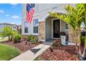 Attractive front porch featuring stone accents, landscaping and an American flag at 5717 Village Center Dr, Lithia, FL 33547
