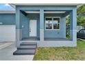 Inviting front porch with blue columns, gray steps, and a bright white door, offering a warm welcome at 6097 Vermont Ave, New Port Richey, FL 34653