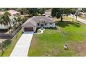 An aerial view showcases this home with a long driveway, two-car garage, and a green, expansive front lawn at 9416 Bullfrog Court, Gibsonton, FL 33534