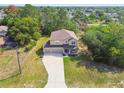 Aerial view of a charming two-story home with a long driveway, and surrounded by trees at 14282 Coronado Dr, Spring Hill, FL 34609