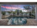 Screened pool with palms and view of a colorful dusk sky, and a raised spa at 4915 Augusta Ave, Oldsmar, FL 34677