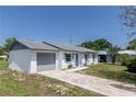 View of single-story home featuring a well-maintained lawn and a convenient attached garage at 5341 Tangerine Dr, Zephyrhills, FL 33542