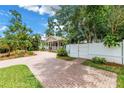 Well-manicured lawn, a charming home with a covered porch, and a brick driveway behind a white fence at 546 26Th N Ave, St Petersburg, FL 33704
