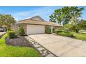 Lovely home featuring a 2-car garage, concrete driveway, stone details, tile roof, and a lush, green lawn at 7032 Pelican Island Dr, Tampa, FL 33634