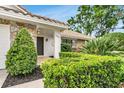 Charming front entrance featuring a tiled porch, stone accents, manicured bushes, and a well-maintained green lawn at 7032 Pelican Island Dr, Tampa, FL 33634
