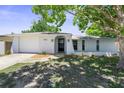 Inviting single-story home with a well-manicured lawn, arched doorway, and attached one car garage at 7215 San Moritz Dr, Port Richey, FL 34668