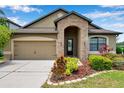 Inviting single-story home with a stone-accented entrance, well-manicured landscaping, and attached two-car garage at 11878 Thicket Wood Dr, Riverview, FL 33579