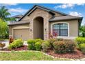 Charming home featuring a stone-arched entryway, complemented by lush greenery and a neatly maintained lawn at 11878 Thicket Wood Dr, Riverview, FL 33579