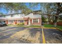 Exterior view of townhome with visible parking and grassy lawn featuring brick and siding, white trimmed windows and doorway at 12780 N 57Th St, Tampa, FL 33617