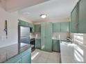 Well-lit kitchen with stainless steel appliances, light countertops, and vintage green cabinetry at 13125 Wilcox Rd # 16202, Largo, FL 33774
