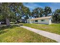 Lovely home with well-kept lawn, mature trees, a sidewalk, and a blue garage door at 1573 Cumberland Ln, Clearwater, FL 33755