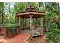 Wooden gazebo with seating offers a serene spot in the wooded backyard at 2279 Ranchette Ln, Dunedin, FL 34698