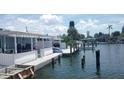 Waterfront patio with white railings, dock, boat lift, and lush tropical surroundings at 28 Seaside Ct, Holmes Beach, FL 34217