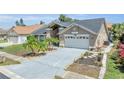 Well-maintained single-Gathering home with a two-car garage, lush landscaping, and a freshly painted driveway at 332 Wood Dove Ave, Tarpon Springs, FL 34689