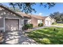 Exterior shot of home with green lawn, driveway, and attached one-car garage at 35229 Janine Dr, Zephyrhills, FL 33541