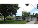 Lovely home featuring green lawn, mature trees, and a long driveway leading to an attached garage at 4105 W Oakellar Ave, Tampa, FL 33611